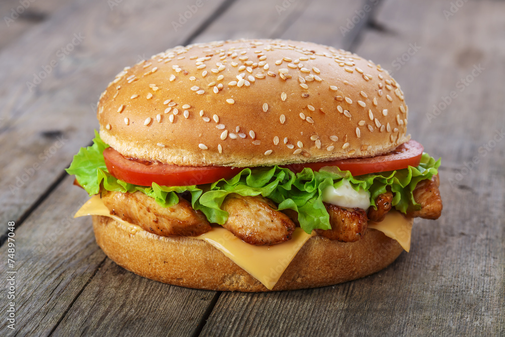 hamburger with chicken and cheese on a wooden surface hamburger with chicken and cheese on a wooden surface