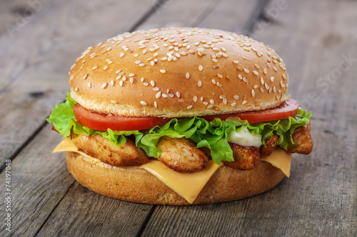 hamburger with chicken and cheese on a wooden surface