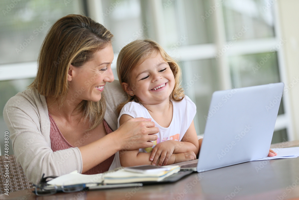 Little girl looking at laptop computer with her mom Little girl looking at laptop computer with her mom