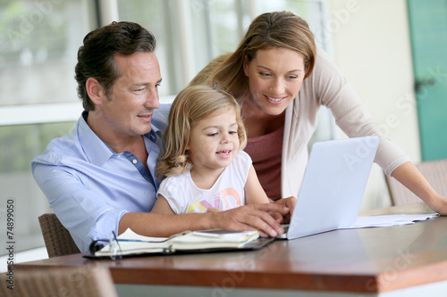 Parents with little girl looking at pictures on computer © goodluz