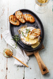 Baked Camembert cheese with toasted bread on cast-iron frying pa
