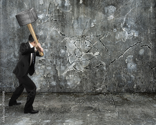Photos businessman using sledgehammer cracking wall broken on concrete