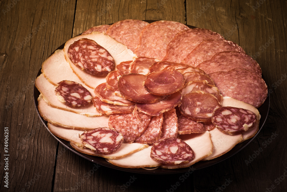 Obraz premium plate with different sliced sausage on an old wooden table