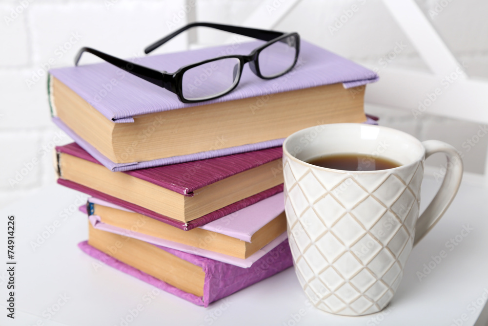 Fototapeta premium Pile of books with cup and glasses