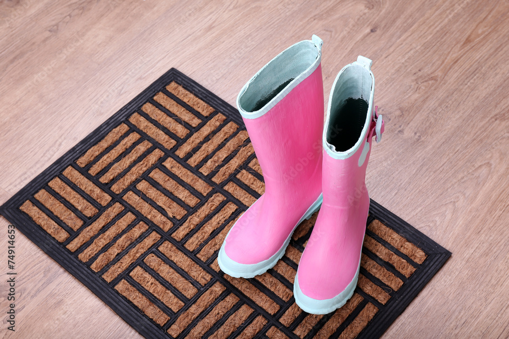 Fototapeta premium Pink wellington boots on door mat in room