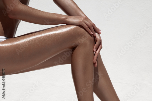 Beautiful woman tan legs. Against white wall.