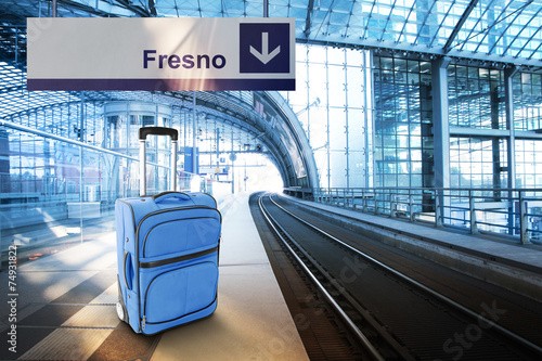Departure for Fresno. Blue suitcase at the railway station