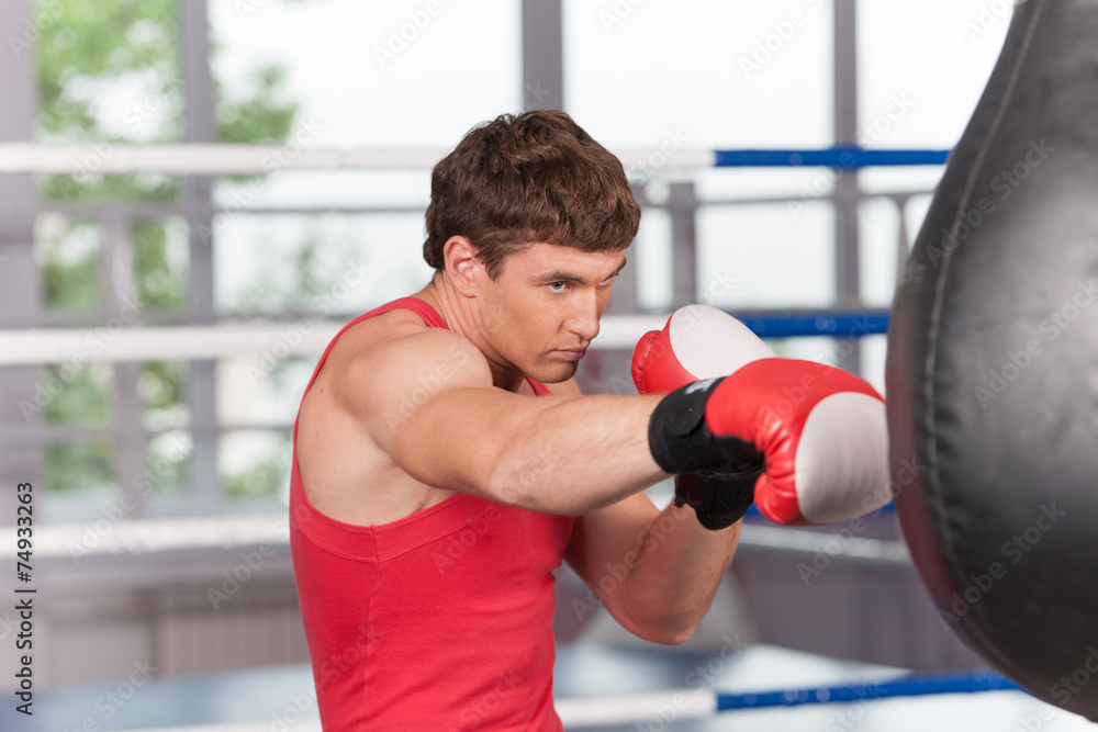 Boxer doing some training on punching bag at gym.