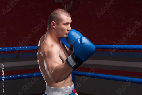 Handsome muscular young man wearing boxing gloves.