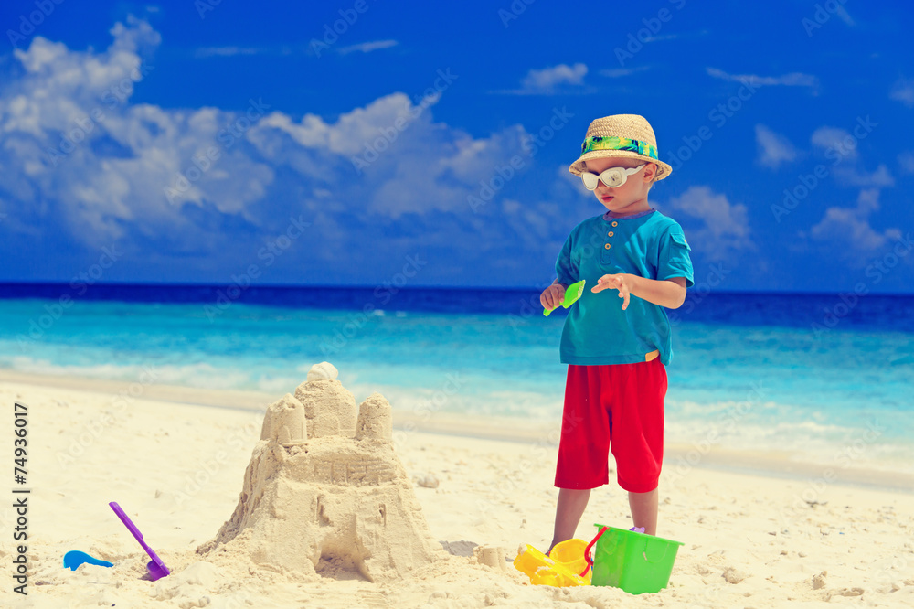 little boy building sand castle on beach little boy building sand castle on beach