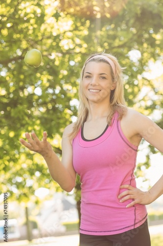 Fit blonde tossing green apple