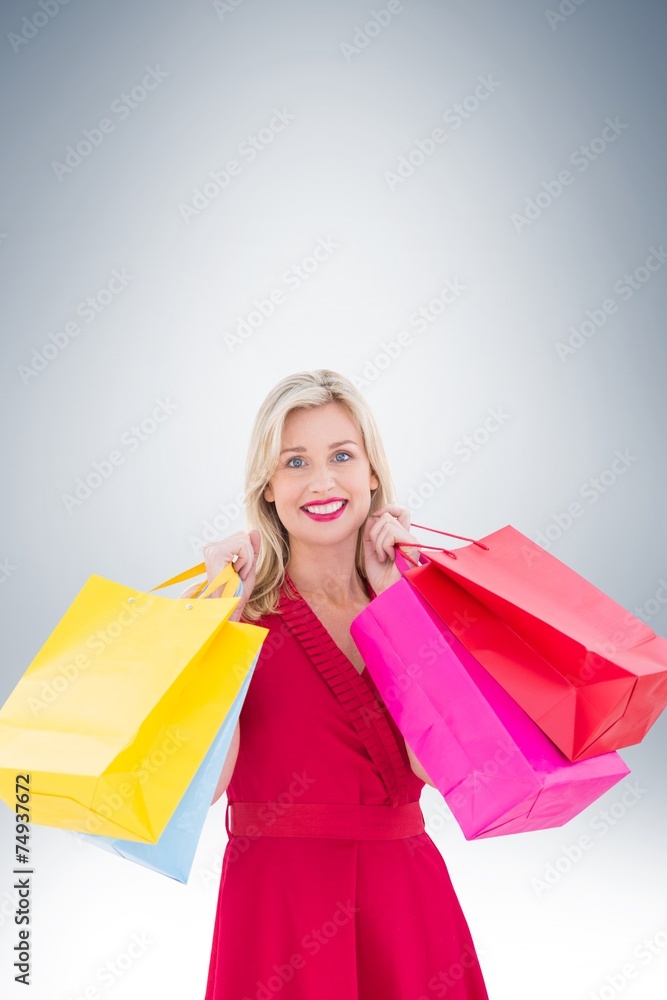 Stylish blonde in red dress holding shopping bags