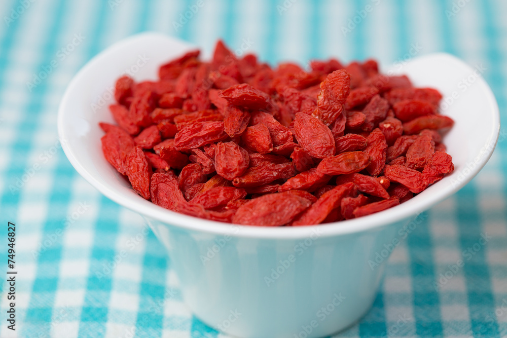 dried goji berries in white bowl on checked fabric dried goji berries in white bowl on checked fabric