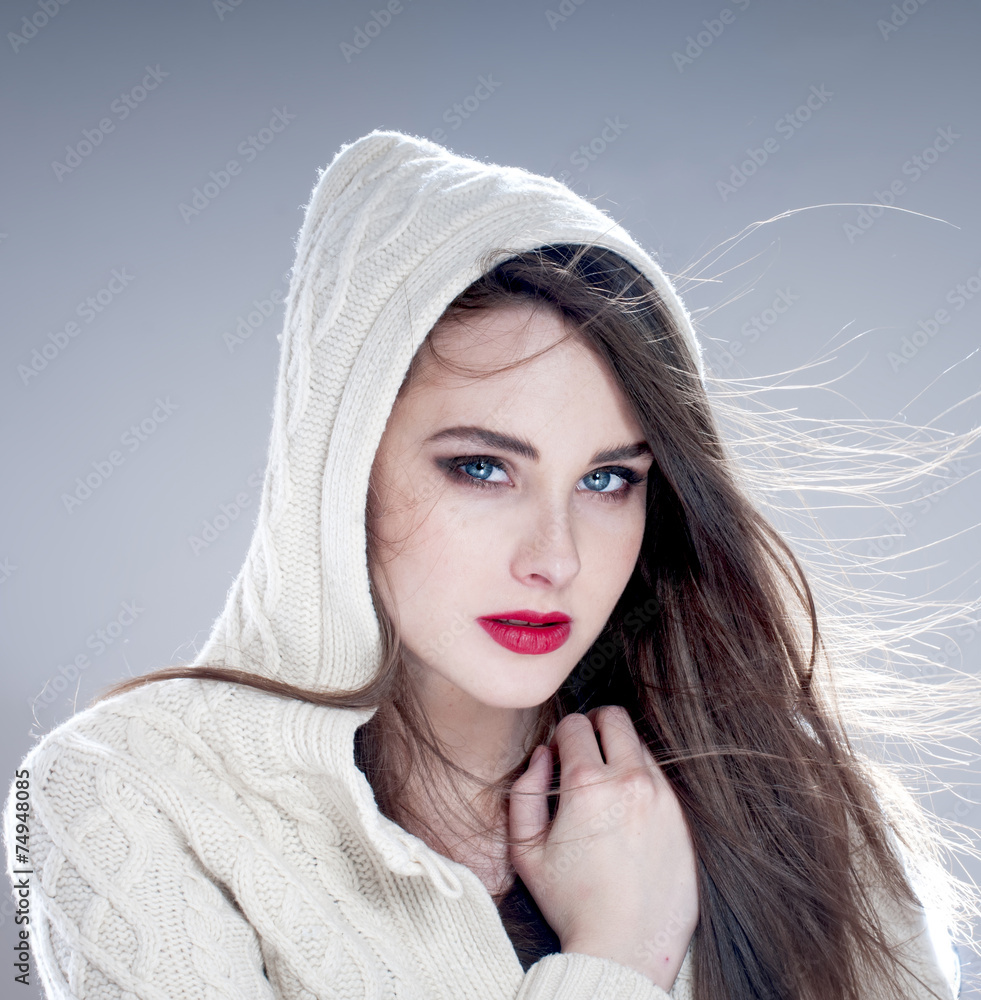 Obraz premium Beautiful charming woman in hood, over blue background.