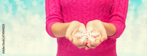 close up of woman in sweater holding snowflake