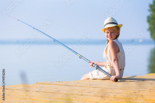 Girl in a dress and a hat with a fishing rod