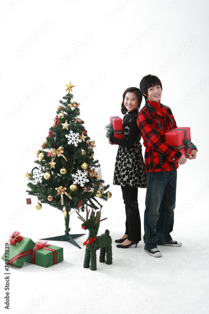 크리스마스 트리 옆에 있는 젊은 사람들