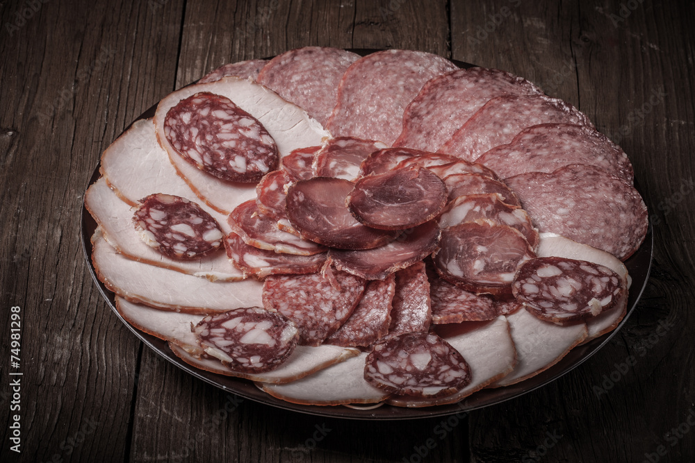 Obraz premium plate with different sliced sausage on an old wooden table
