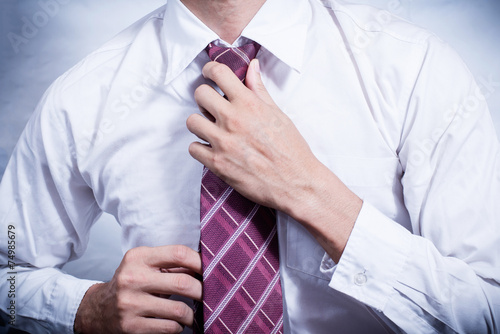 Close-up of a businessman adjusting his necktie
