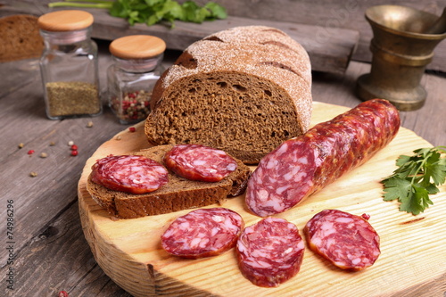 Sliced salami and bread on a cutting board