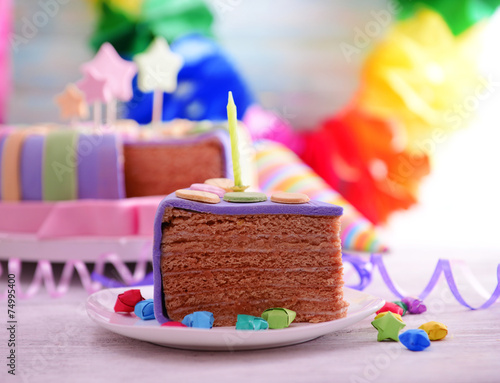 Delicious piece of birthday cake on table on bright background
