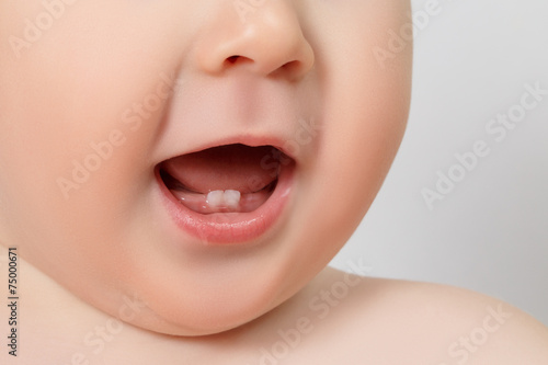 Close-up of a smiling baby showing their first two teeth