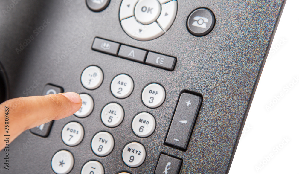 Female hand dialing numbers of desktop telephone Female hand dialing numbers of desktop telephone