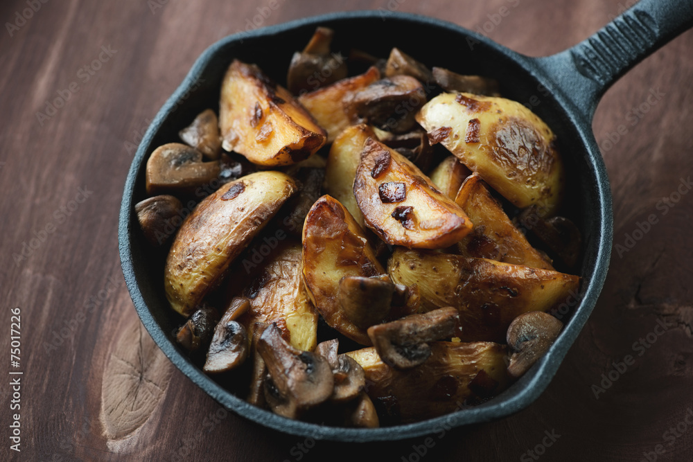 Roasted potatoes with peel and mushrooms in a frying pan Roasted potatoes with peel and mushrooms in a frying pan