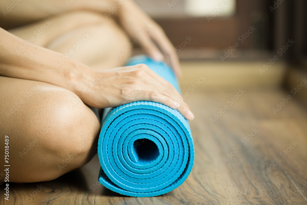 Young woman holding a yoga mat - obrazy, fototapety, plakaty 