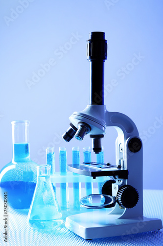Microscope and test tubes on table, on color background