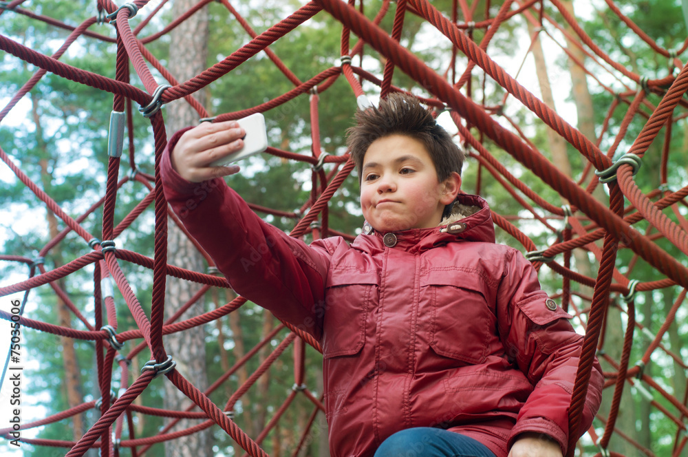 Boy with phone on the playground in the park Boy with phone on the playground in the park