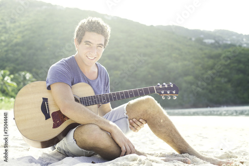 Young men playing guitar on the beach photo