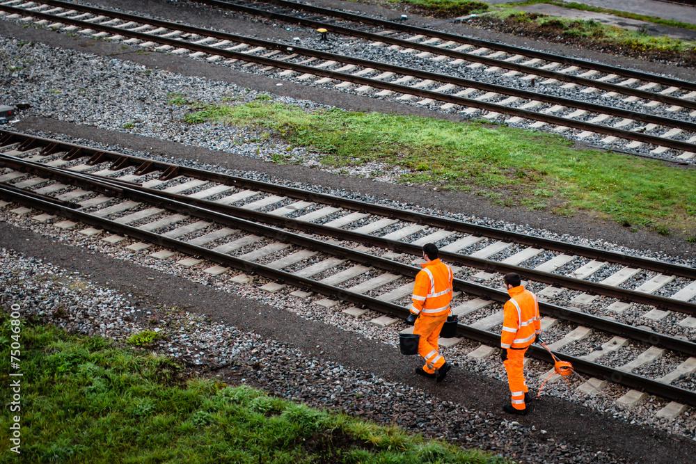 Two workers walking along railroad tracks - obrazy, fototapety, plakaty 