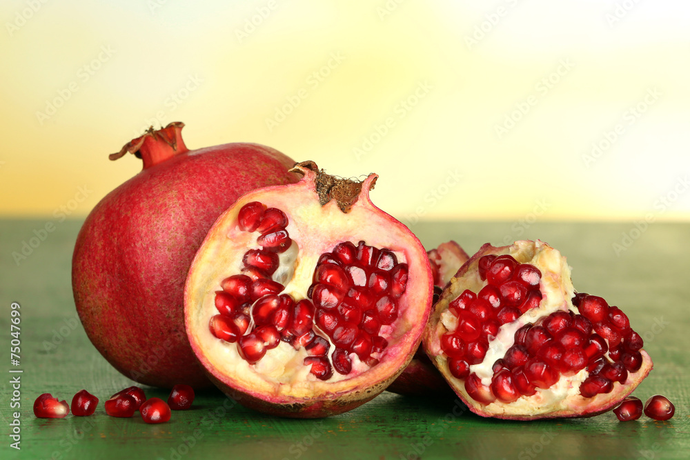 Juicy ripe pomegranates on green wooden table Juicy ripe pomegranates on green wooden table
