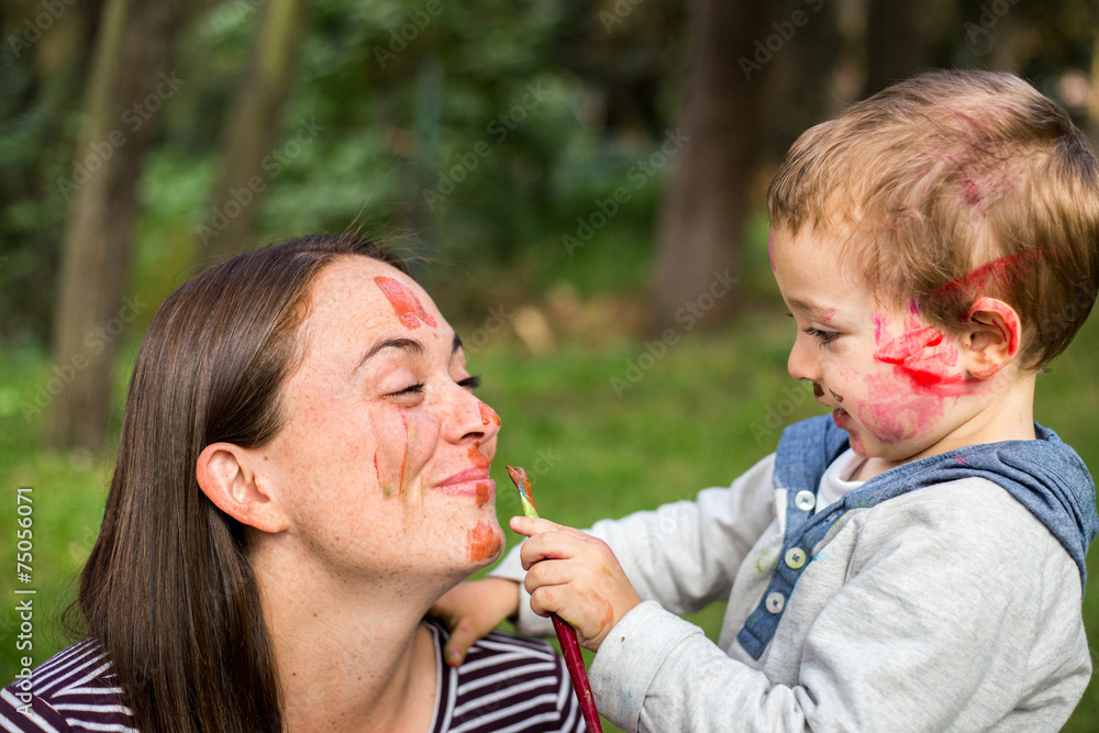 Happy child painting his mother´s face in the park Happy child painting his mother´s face in the park