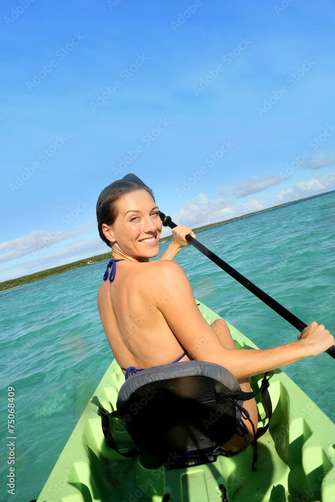 Back view of beautiful woman paddling in canoe