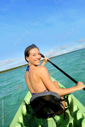 Back view of beautiful woman paddling in canoe