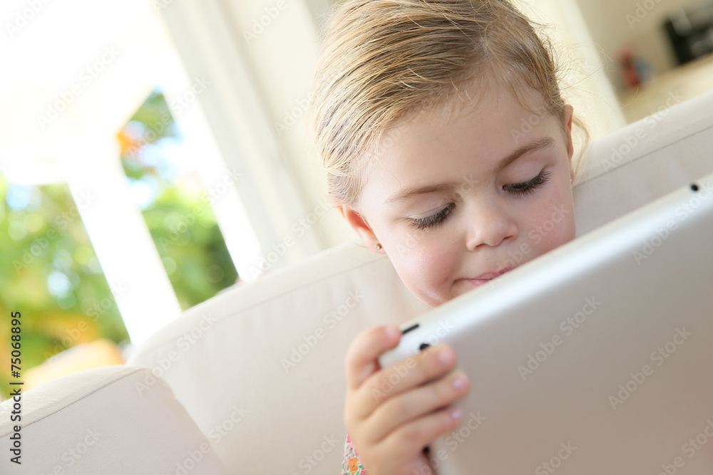 Little girl in sofa connected with digital tablet Little girl in sofa connected with digital tablet