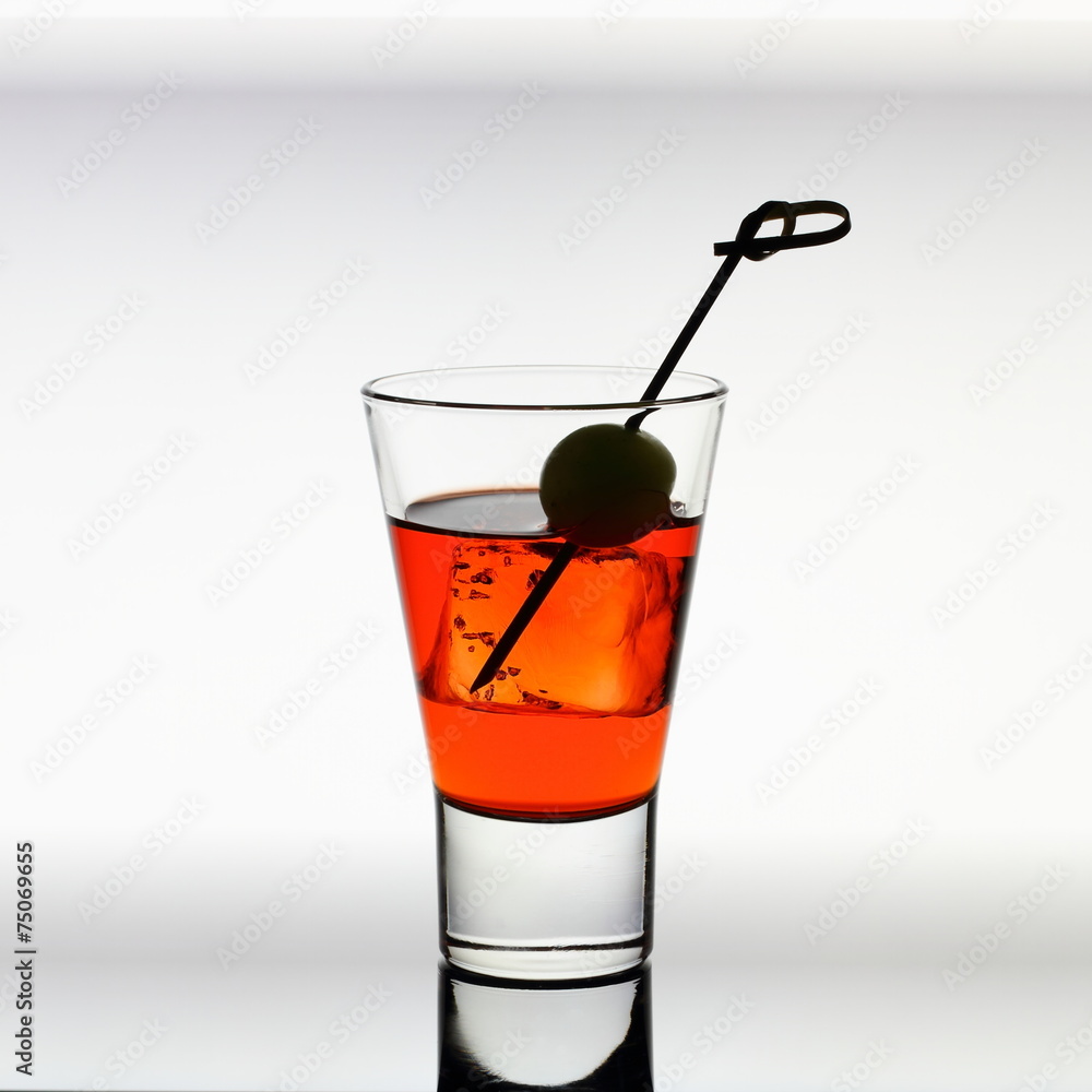 Short drink glass with red liquid, olive, ice cubes Short drink glass with red liquid, olive, ice cubes