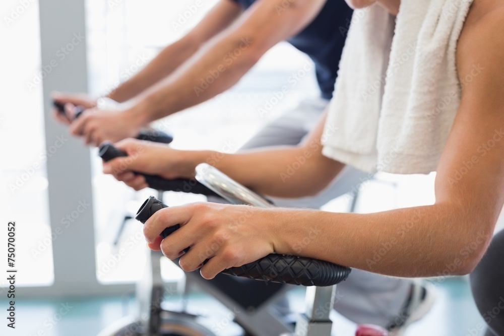 Mid section of fit couple working on exercise bikes at gym Mid section of fit couple working on exercise bikes at gym