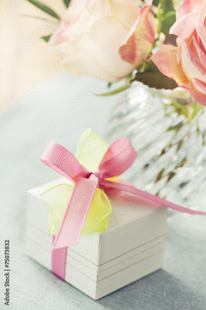 Gift box decorated with bow and roses in vase Gift box decorated with bow and roses in vase