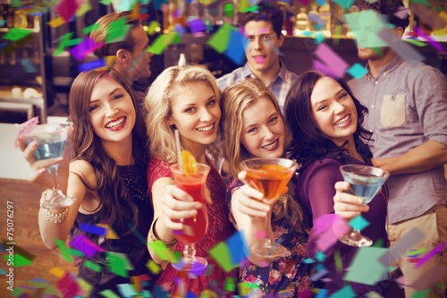 Composite image of happy friends drinking cocktails together