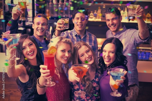 Composite image of happy friends drinking cocktails together