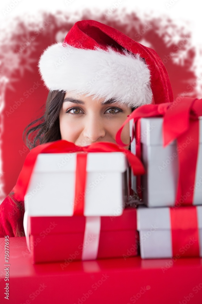 Composite image of festive brunette holding stack of gifts