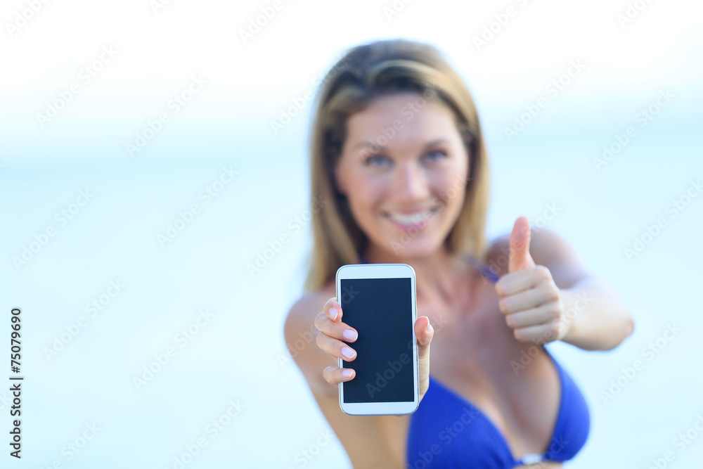 Beautiful woman in bikini showing smartphone to camera Beautiful woman in bikini showing smartphone to camera