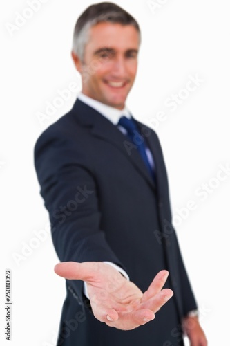 Smiling businessman in suit with arm out