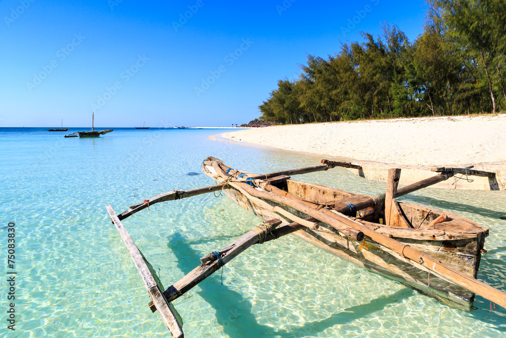 Traditional fisherman boat lying near the beach in clear water - obrazy, fototapety, plakaty 