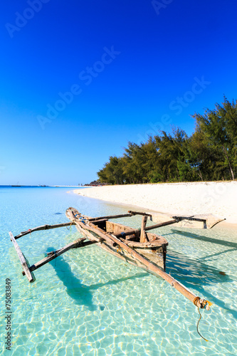 Traditional fisherman boat lying near the beach in clear water