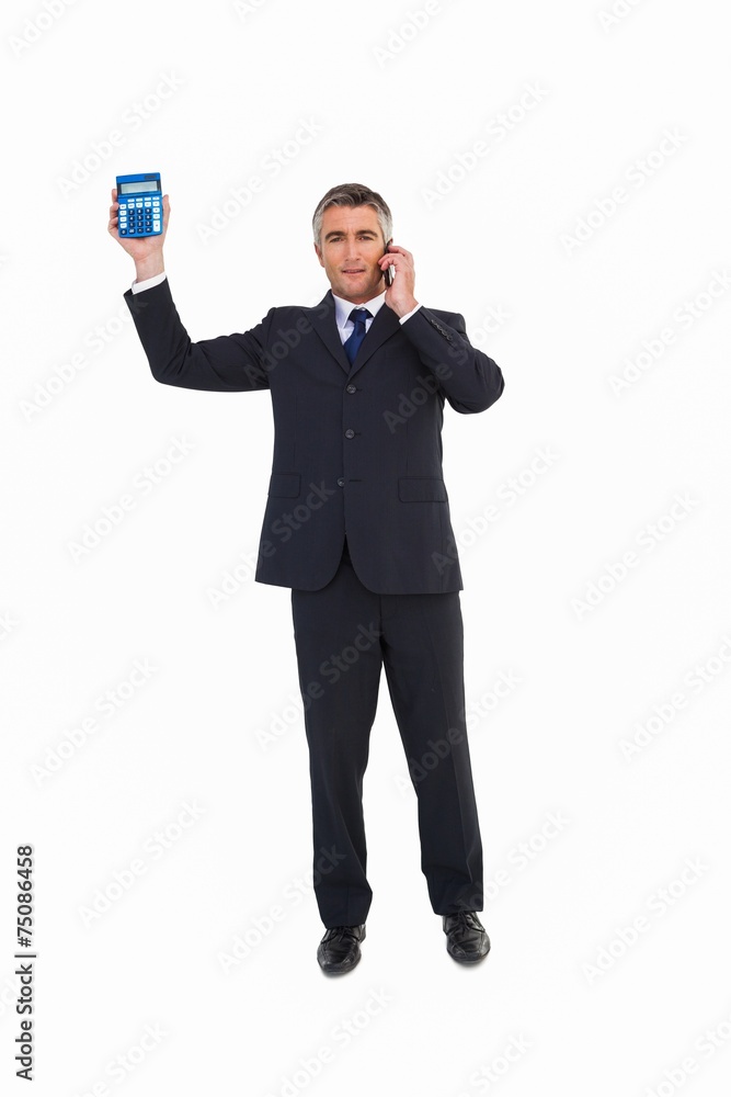 Businessman on the phone showing a calculator Businessman on the phone showing a calculator