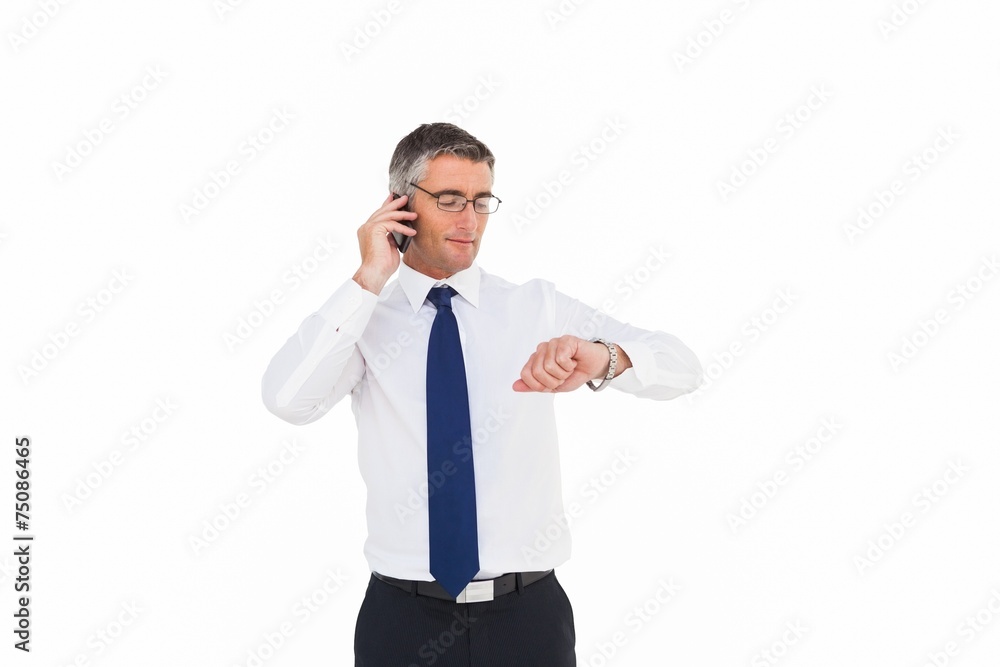 Businessman on the phone looking at his wrist watch Businessman on the phone looking at his wrist watch
